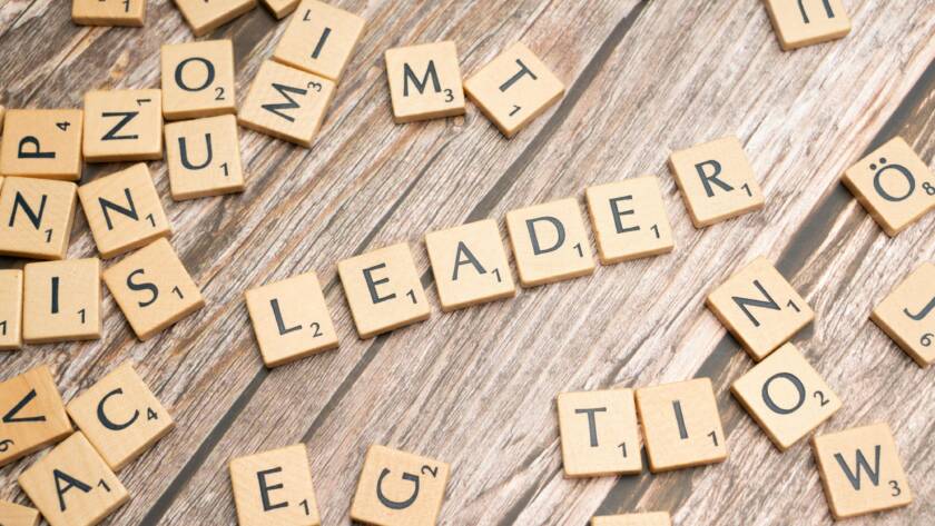 Wooden Scrabble tiles on a table spelling 'Leader' symbolize leadership and strategy.