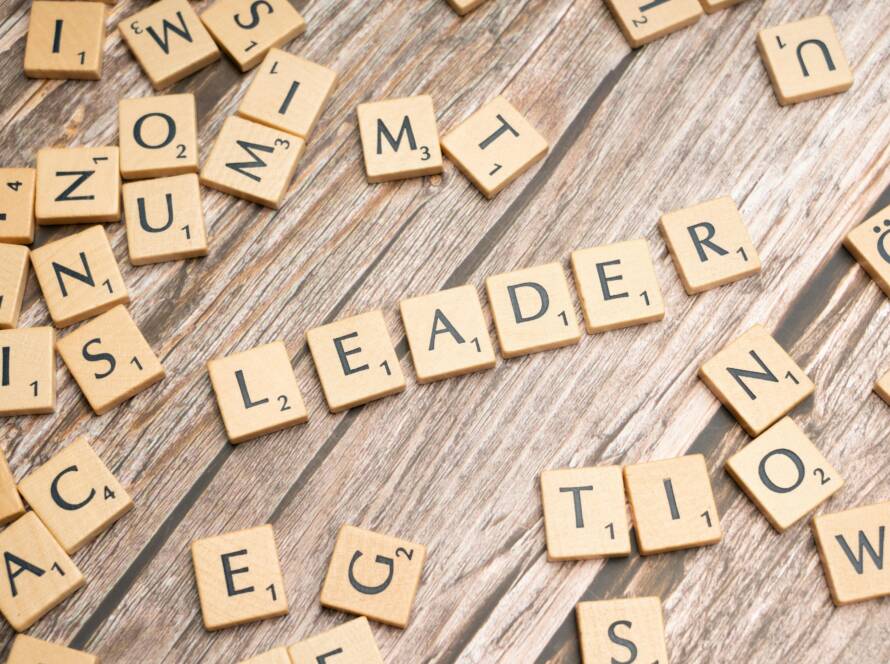 Wooden Scrabble tiles on a table spelling 'Leader' symbolize leadership and strategy.