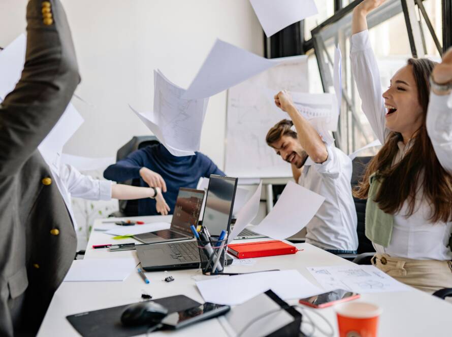 Group of diverse business professionals celebrating success in a modern office setting.
